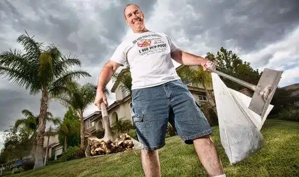 Image of tim stone, founder of scoop masters pet waste removal, holding a shovel of dog poop and a bag of dog poop